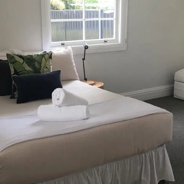 A made bed with rolled towels in a holiday rental