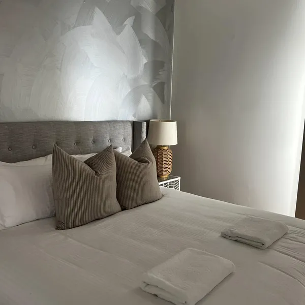 A made bed with a towel folded at the end in a holiday rental