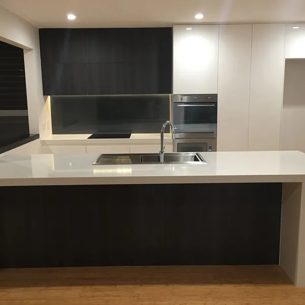 A cleaned white kitchen with a stone bench