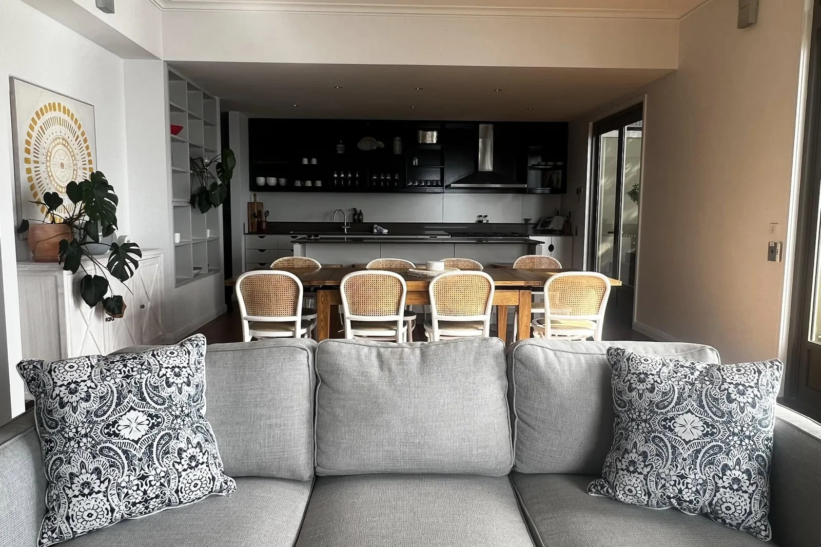A grey lounge with patterned cushions in a bright living room