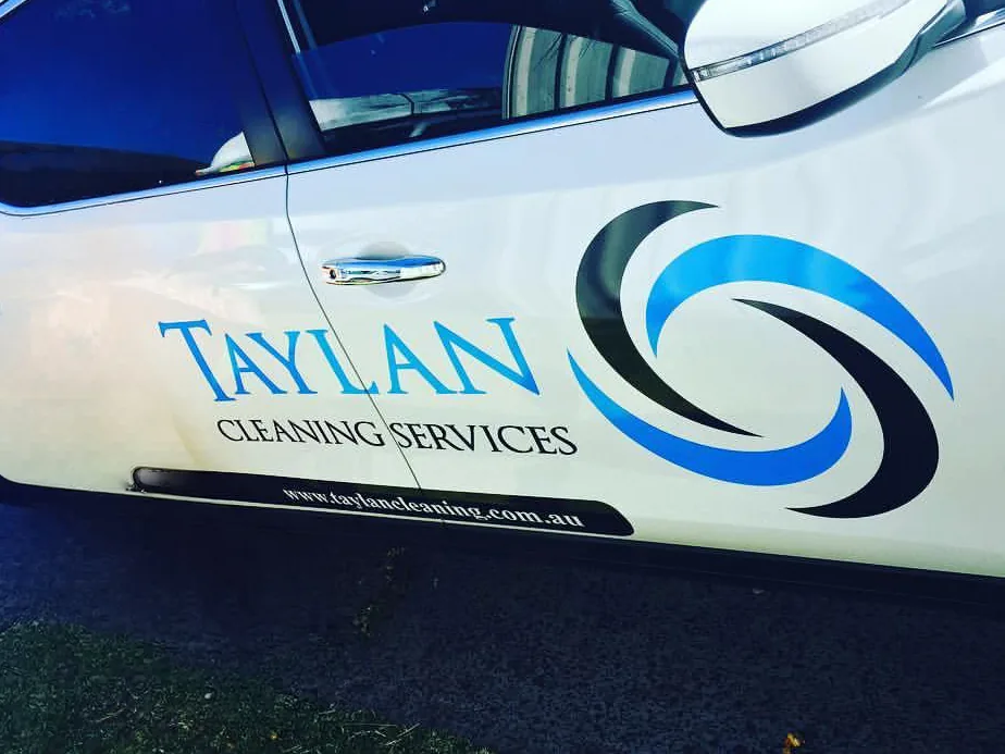 The Taylan Cleaning Services logo on the door of a company vehicle